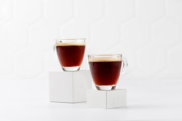 Coffee, two cups with espresso on white podiums and tile background. Aroma, ristretto. Glass of...