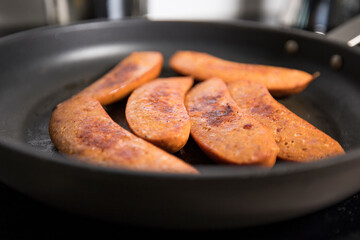 Sausage frying in a frying pan.