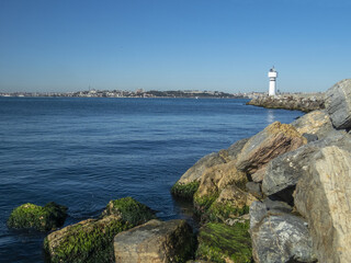 Fototapeta na wymiar Lighthouse tower and Kadikoy harbour, view from MODA park
