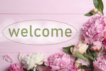 Beautiful peonies and word WELCOME on pink wooden table, flat lay