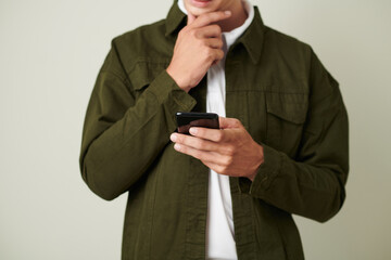 Cropped image of pensive man rubbing chin when deciding what to reply on text message