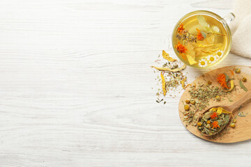 Freshly brewed tea and dried herbs on white wooden table, flat lay. Space for text