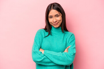 Young hispanic woman isolated on pink background frowning face in displeasure, keeps arms folded.
