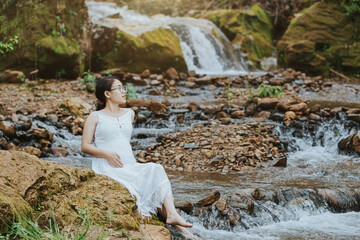 pregnant woman sitting at the waterfall