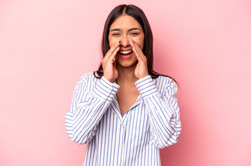 Young hispanic woman isolated on pink background saying a gossip, pointing to side reporting something.