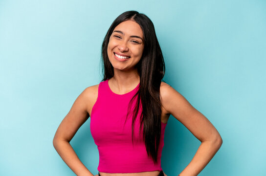 Young hispanic woman isolated on blue background confident keeping hands on hips.