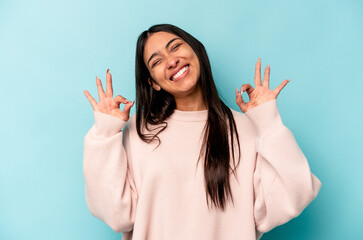 Young hispanic woman isolated on blue background cheerful and confident showing ok gesture.