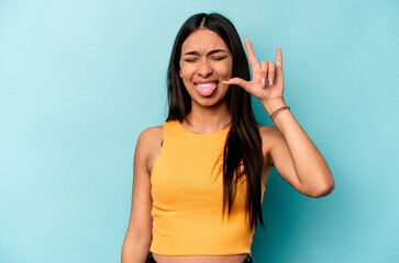 Young hispanic woman isolated on blue background showing rock gesture with fingers