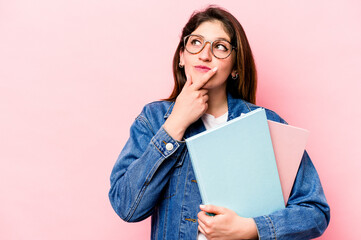 Young student caucasian woman isolated on pink background looking sideways with doubtful and skeptical expression.