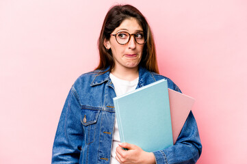 Fototapeta premium Young student caucasian woman isolated on pink background confused, feels doubtful and unsure.