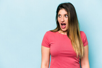 Fototapeta premium Young caucasian woman isolated on blue background being shocked because of something she has seen.