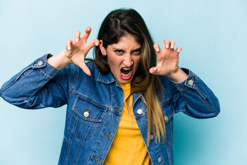 Young caucasian woman isolated on blue background upset screaming with tense hands.