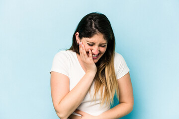 Young caucasian woman isolated on blue background laughs happily and has fun keeping hands on...
