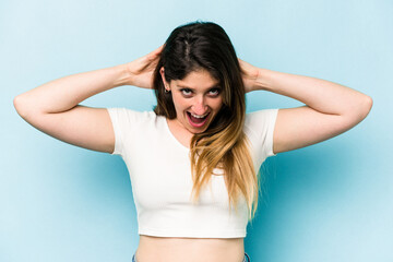 Young caucasian woman isolated on blue background screaming, very excited, passionate, satisfied with something.