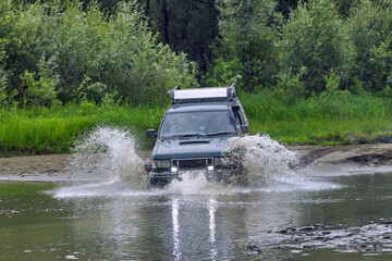 4x4 off-road car crosses a water barrier with splashes at high speed. Extreme off-road tour in the...