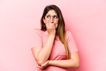 Young caucasian woman isolated on pink background biting fingernails, nervous and very anxious.
