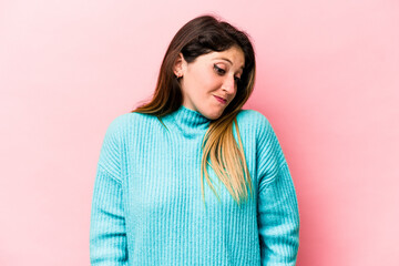 Fototapeta premium Young caucasian woman isolated on pink background shrugs shoulders and open eyes confused.