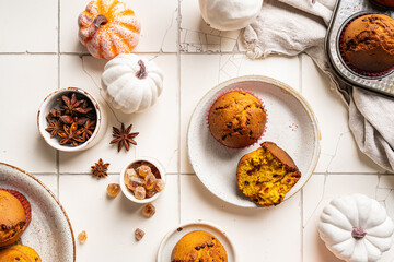 Homemade autumn pumpkin muffins with cinnamon and chocolate on tile background, top view