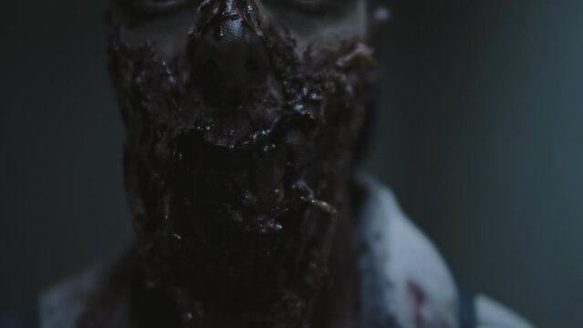Close-up portrait of lower face of spooky male zombie moving his jaw with flesh hanging on it