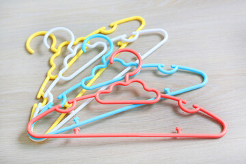 Colored plastic Clothes Hangers on wooden background