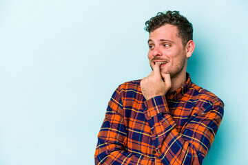 Young caucasian man isolated on blue background relaxed thinking about something looking at a copy space.