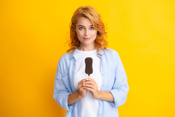 Summer concept. Glad positive woman holds tasty frozen ice cream, enjoys eating delicious cold dessert, poses on yellow background, feels happy.