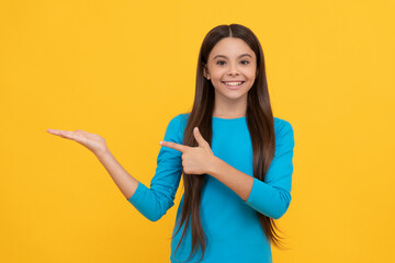 happy child with long hair presenting product and point finger on copy space, advertisement.