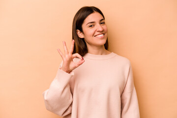 Young hispanic woman isolated on beige background cheerful and confident showing ok gesture.
