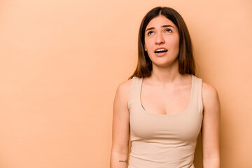 Obraz premium Young hispanic woman isolated on beige background shouting very angry, rage concept, frustrated.
