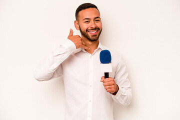 Young hispanic TV presenter isolated on blue background showing a mobile phone call gesture with fingers.