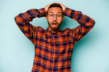 Young hispanic man isolated on blue background screaming, very excited, passionate, satisfied with...