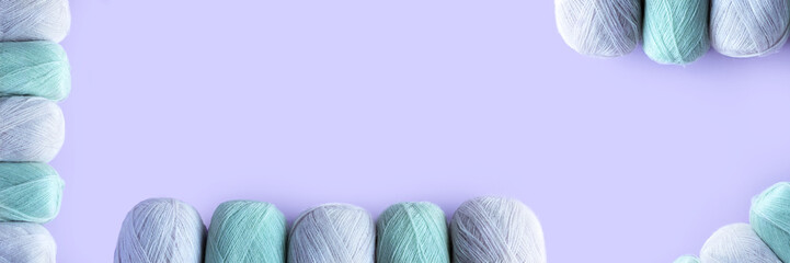 Green and pink yarn threads on a lilac background for knitting warm clothes, banner