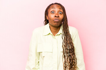 Young african american woman isolated on pink background shrugs shoulders and open eyes confused.