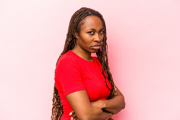 Young african american woman isolated on pink background suspicious, uncertain, examining you.