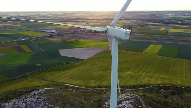 Molino de viento de color blanco con campos de trigo y cebada de colores verdes en el fondo