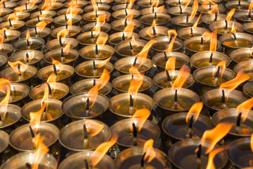 Burning prayer candles in buddhist temple, close up image