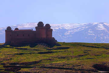 sunset Calahorra castle in Andalusia, Spain. Behind the castle you can see the Sierra Nevada with strong backlight