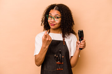 Young African American hairdresser woman isolated on beige background pointing with finger at you...