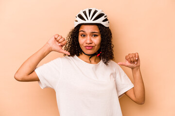 Young hispanic woman wearing a helmet bike isolated on blue background feels proud and self...