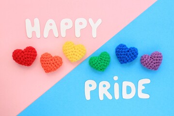 Crochet hearts rainbow and Happy Pride letters on pink and blue background. LGBT flag gay pride...