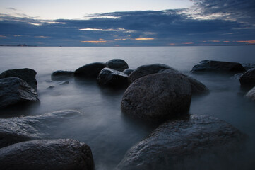 Fototapeta na wymiar Big stones stones on the shore in water at night. Long exposure nature seascape photography