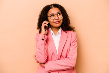 Young African American business woman holding mobile phone isolated on beige background