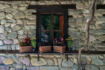 Fototapeta na wymiar a stone wall with a wooden window and beautiful flowers in front of it