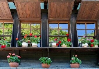 wooden facade of a house with windows and flowers on them