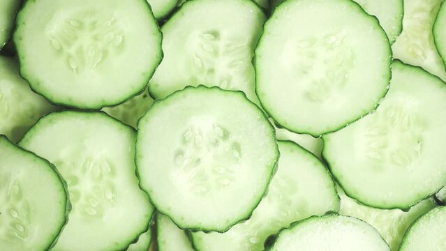 Slow motion of rotation ripe green sliced cucumbers. Circles of fresh cucumbers as food background. Concept of proper nutrition or healthy lifestyle and diet. Macro shot.