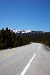 Naklejka premium American Road with snow coverd mountains in the back