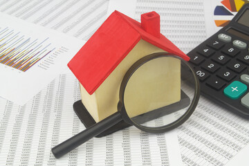 House model with magnifying glass and calculator on financial documents. Investments and searching...