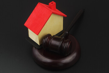 Real estate laws and auction concept. Wooden judge gavel and house model on black background.	