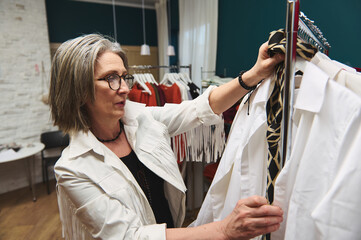 Mature European woman fashion designer stylist couturier tailor in a clothing design workshop and...