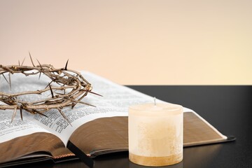 A brightly shining candle, a crown of thorns symbolizing the crucifixion of Jesus Christ, and the...
